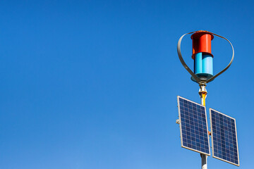 Wind generator and solar panels against the blue sky, the concept of energy saving technologies, copy space