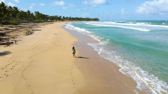 black woman walking along the sandy beaches of Punta Cana Dominican republic during a bright Sunday day on holiday. the clear blue water beautiful and  great for tourist.