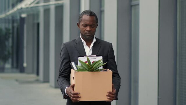 Corporate discrimination. Outdoor portrait of upset african american man employee standing near office after dismissal
