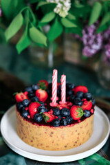 Cheesecake with strawberries and blueberries, close-up, on a background of lilacs. Vertical orientation.