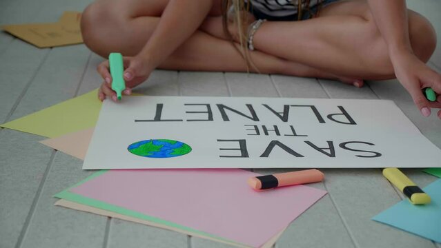 Close-up slow motion of female hands drawing posters banner im save the planet