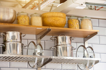 Pots and lids with jars for food storage on kitchen shelves.