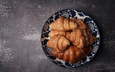 delicious croissants on parchment on a dark concrete background,coppy space.
