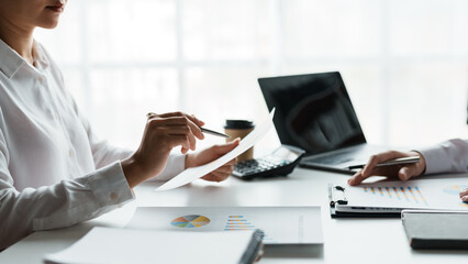 Two business people point to graphs and charts to analyze market data, balance sheet, account, net profit to plan new sales strategies to increase production capacity.