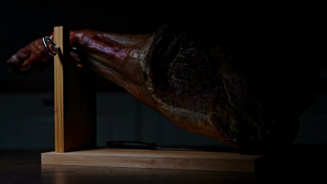 Dry-cured spanish ham appears from darkness.