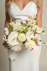 Vertical unrecognizable cropped stylish, fashionable woman body in white dress with low neck, hold posh bunch of flowers