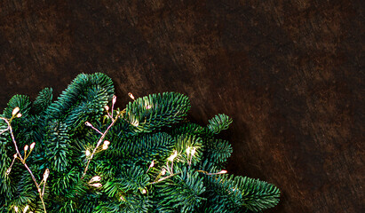 Christmas tree brunches with sparkling lights  close up on wooden background,  top view, copyspace....