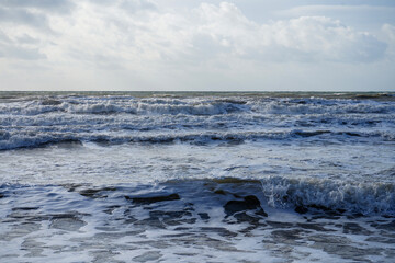 Fototapeta na wymiar Waves crashing in the ocean with a cloudy sky