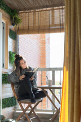 Young woman reading a book on the terrace of her house