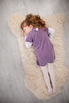A cute little girl is lying on a fur blanket, top view