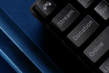 Fragment of a trendy black computer keyboard with game streaming terms and symbols. The concept of technologies for online streaming of computer games and donations. Macro.