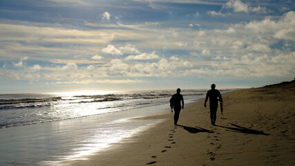Two silhouetted surfers head out to the beach in Kill Devil Hills on the Outer Banks to battle the...