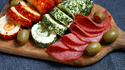Snacks in Italian style on a wooden board. Cheese rolls, salami, olives.