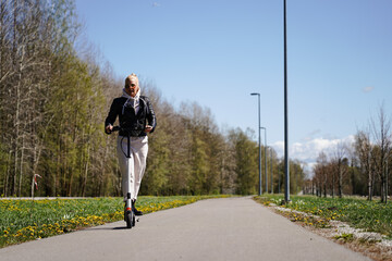 A girl rides a scooter along a bike path on a spring day.