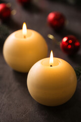 Two round candles with Christmas decoration on a dark background