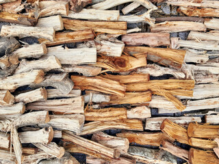 Background of dry firewood logs of different sizes and colors. Full frame of dry wooden dowels. Pile of firewood and wood shavings. Natural wooden background.