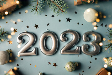 Numbers of year 2023 made by candles. Fir tree, gift box, holiday decoration on blue background....