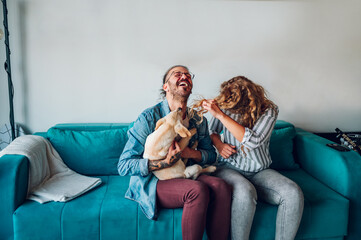 Couple petting their adopted dog while sitting on the couch at home