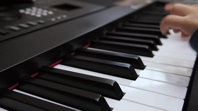 Children's fingers play on the keys of a piano synthesizer. Selective focus on piano keys. High quality FullHD footage