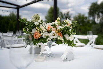 Table centerpiece with white and peach rustic floral arrangement in glass vase. Rustic wedding table.