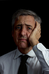 Fototapeta premium headache. concern. concentration. portrait. dark key. Man with gray hair, tie and white shirt.