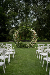 Wedding ceremony. Very beautiful and stylish roundwedding arch, decorated with various fresh flowers, standing in the garden.