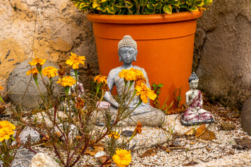 A close up of a small Buddha statue in a autumn garden.