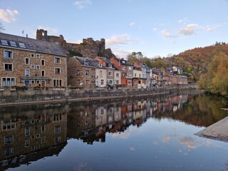 Riverbank of picturesque village of La Roche En Ardenne (Belgian Ardennes) along the river Ourthe at golden hour (sunset) with reflection of stone houses in the water