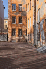 courtyard of an old stone orange house. shadows of trees on the ground and walls. St. Petersburg, Petrogradskaya