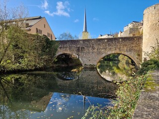 Reflection of church spire tower in river flowing through Luxembourg city