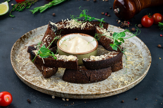Beer food rye croutons with cheese and garlic sauce, garnished with green peas on a plate.
