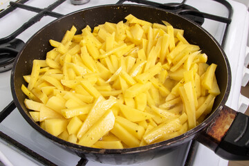 Fried potatoes in frying pan on stove