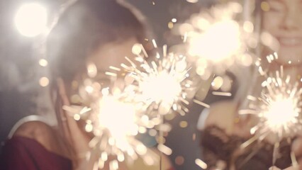 Beautiful woman holding christmas sparklers in hands. Friends celebrating by waving fireworks, enjoying party on New Years or Christmas Eve night. Happy group of people enjoying party in Xmas evening. - Powered by Adobe