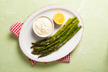 Top view of roasted green asparaguson white plate vegan food