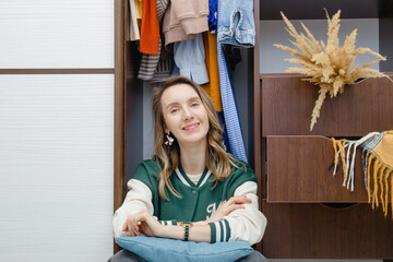Woman sitting in closet. Wardrobe organization.