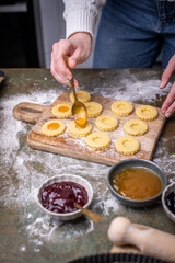 Weihnachten Plätzchen backen, Weihnachtsbäckerei, frisch gebackene Plätzchen mit verschiedenen Marmeladen füllen, Spitzbuben Plätzchen