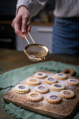 Weihnachten Plätzchen backen, Weihnachtsbäckerei, frisch gebackene Plätzchen mit Puderzucker bestreuen