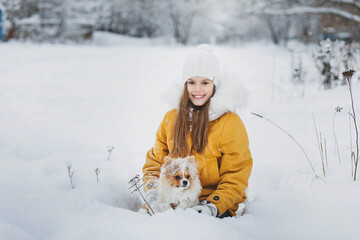 A girl plays with a dog in the snow