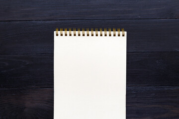 Blank notepad sheet on a dark wooden surface. Nice mock up for designers art work.