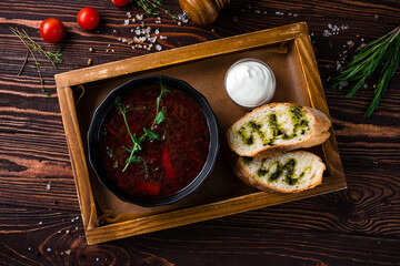 Fototapeta na wymiar Red borscht soup made from beets, potatoes, cabbage, onions and spices with sour cream and bread.