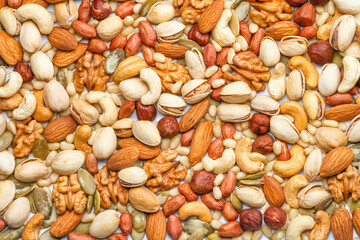 Background from different types of nuts and seeds - peeled walnut, hazelnuts, peeled peanut, pine...