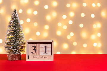 wooden calendar 31 december on red background and lights background