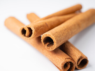 Close-up. Two cinnamon sticks lie beautifully on top of each other on a white background. On the cut, the structure of the cinnamon stick is clearly visible. Close-up concept of cinnamon sticks.