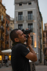 Tourist hispanic man holding a photo camera and taking a photo in an old city