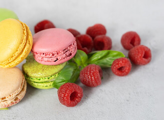 colored macarons and raspberries close-up on a gray background with copy space