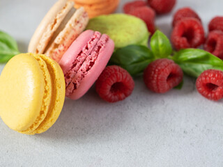 Fruity Macaroons, macarons with Raspberries close-up on a gray background with soft focus. Confectionery with berries.