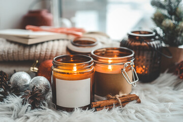 Candle with an empty label, a place for your logo, in a Christmas interior