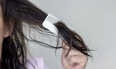woman applying serum oil on wet hair with pipette or using white comb to disentangle isolated.healthy strong hair,growth stimulation stop fall shiny.top of head forehead lateral view.after pregnancy