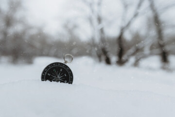 Round compass in the snow, space for text. Navigation in the winter forest. Orienteering concept in...