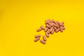 Simple pile of brown pills stacked on yellow background